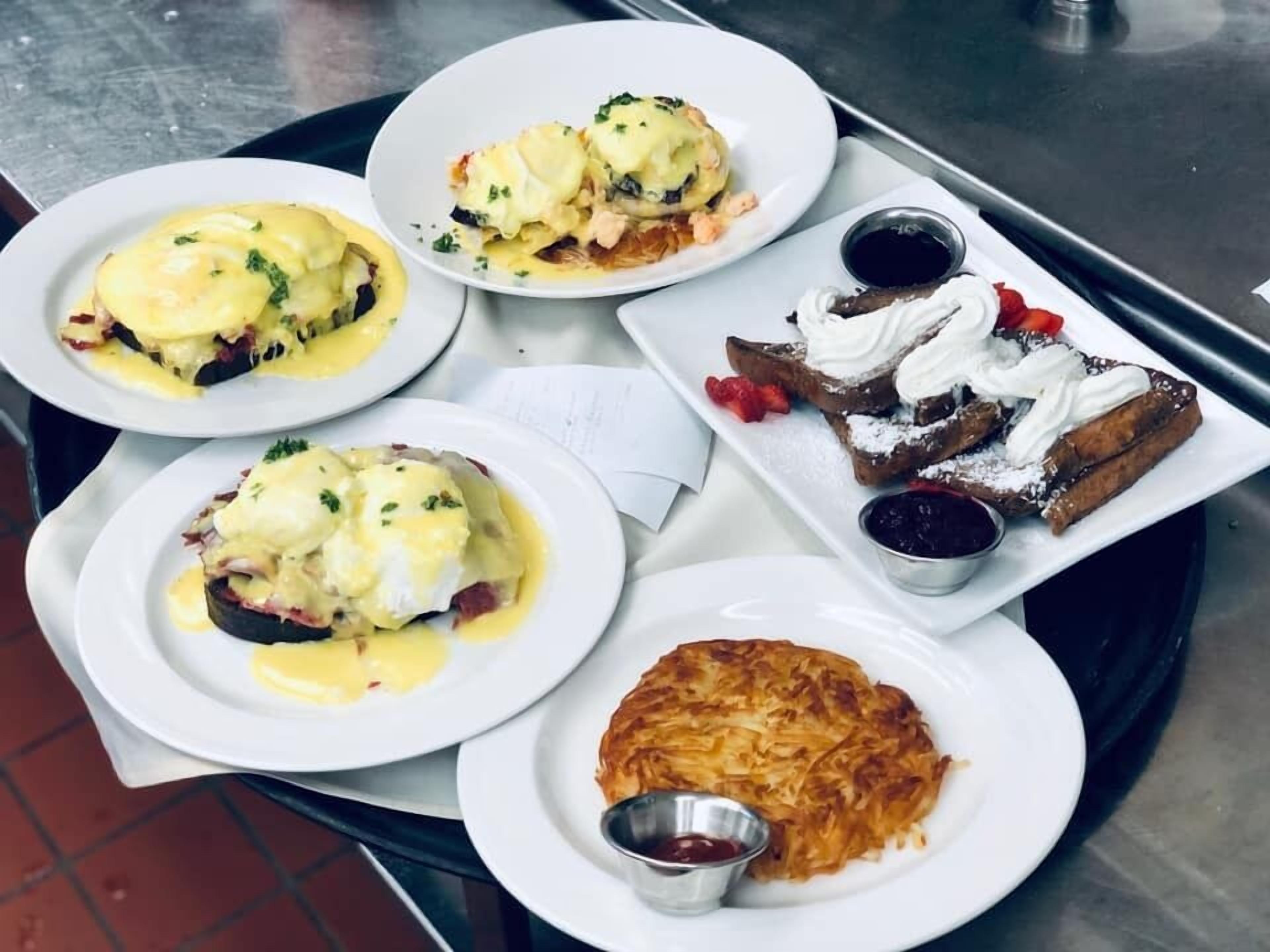 A tray with various breakfast dishes including eggs benedict, French toast, and pancakes.