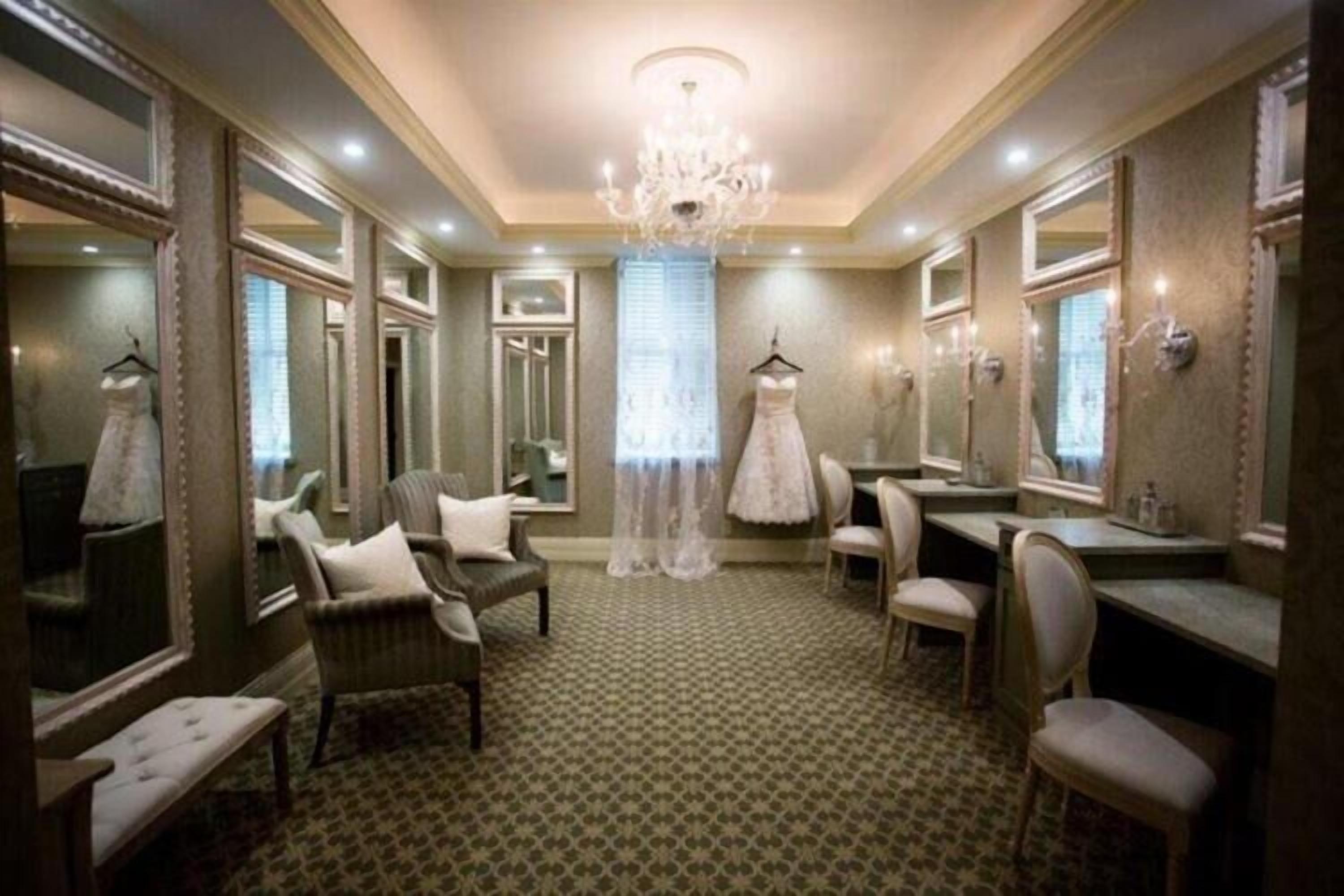 A room with a patterned carpet, a chandelier, and multiple mirrors on the walls.