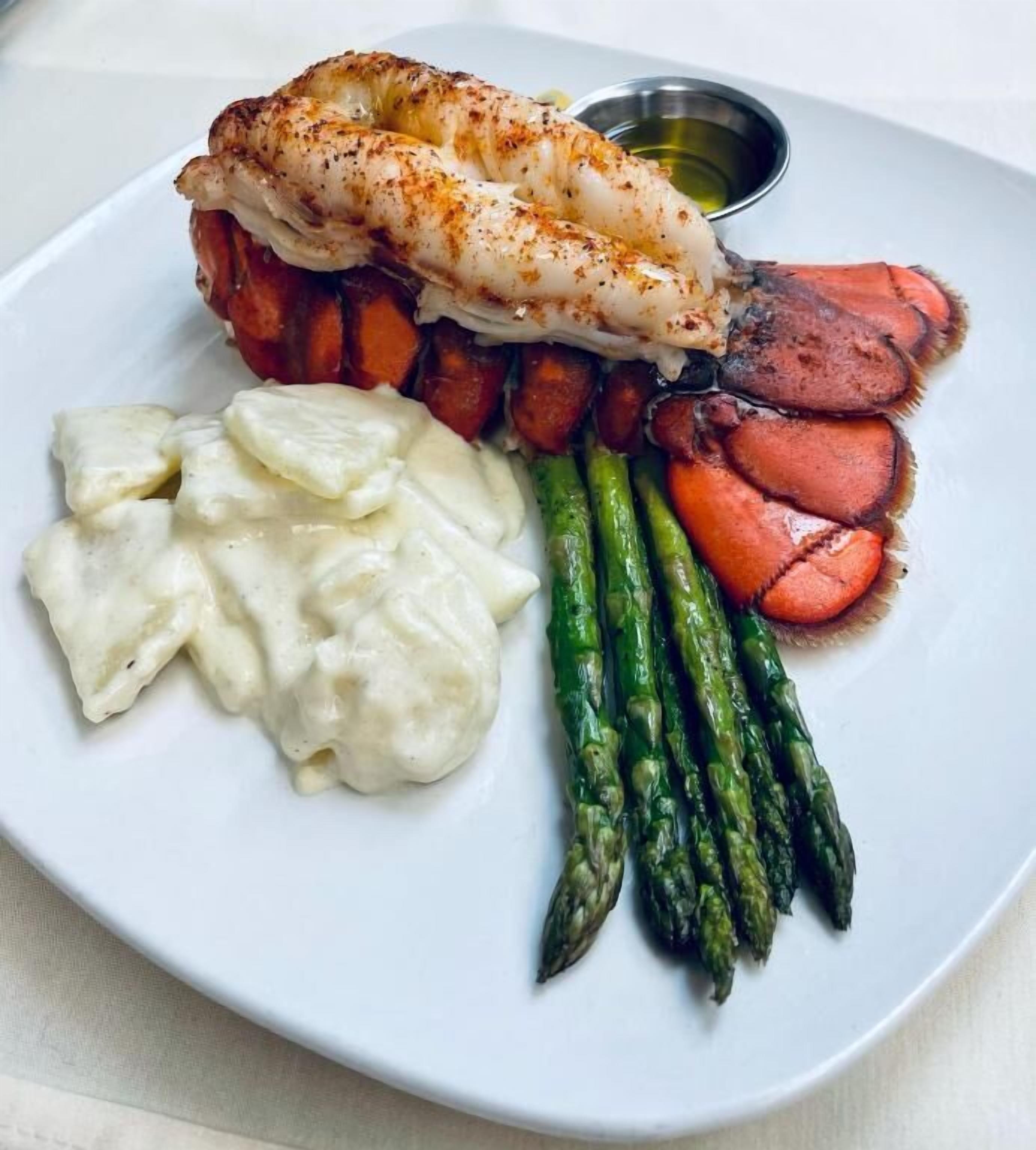A plate with grilled fish, asparagus, carrots, and dumplings.