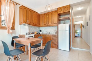 A modern kitchen with wooden cabinets, a dining table with chairs, and a refrigerator.