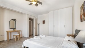 Ein Schlafzimmer mit einem Bett, einem Schreibtisch, einem Stuhl, einer Stehlampe und einem Kleiderschrank.