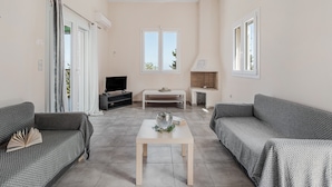 Ein Wohnzimmer mit zwei Sofas, einem Couchtisch, einem Fernseher und einem Kamin.