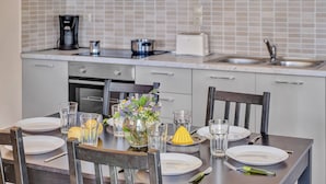 Una cocina con una mesa de comedor para dos personas, una cafetera, un tostador y un lavabo.