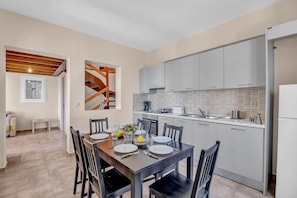 Una cocina moderna con gabinetes grises, una mesa de comedor preparada para cuatro personas y un ventanal.