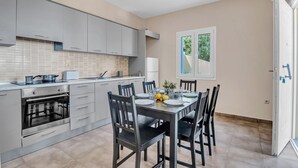 Una cocina moderna con armarios grises, horno empotrado y una mesa de comedor preparada para cuatro comensales.