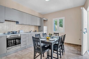 Une cuisine moderne avec des meubles gris, un four encastré et une table à manger pour quatre personnes.