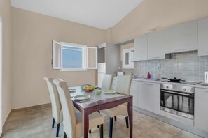 Eine moderne Küche mit weißen Schränken, einem eingebauten Backofen und einem Essbereich mit Tisch und Stühlen.