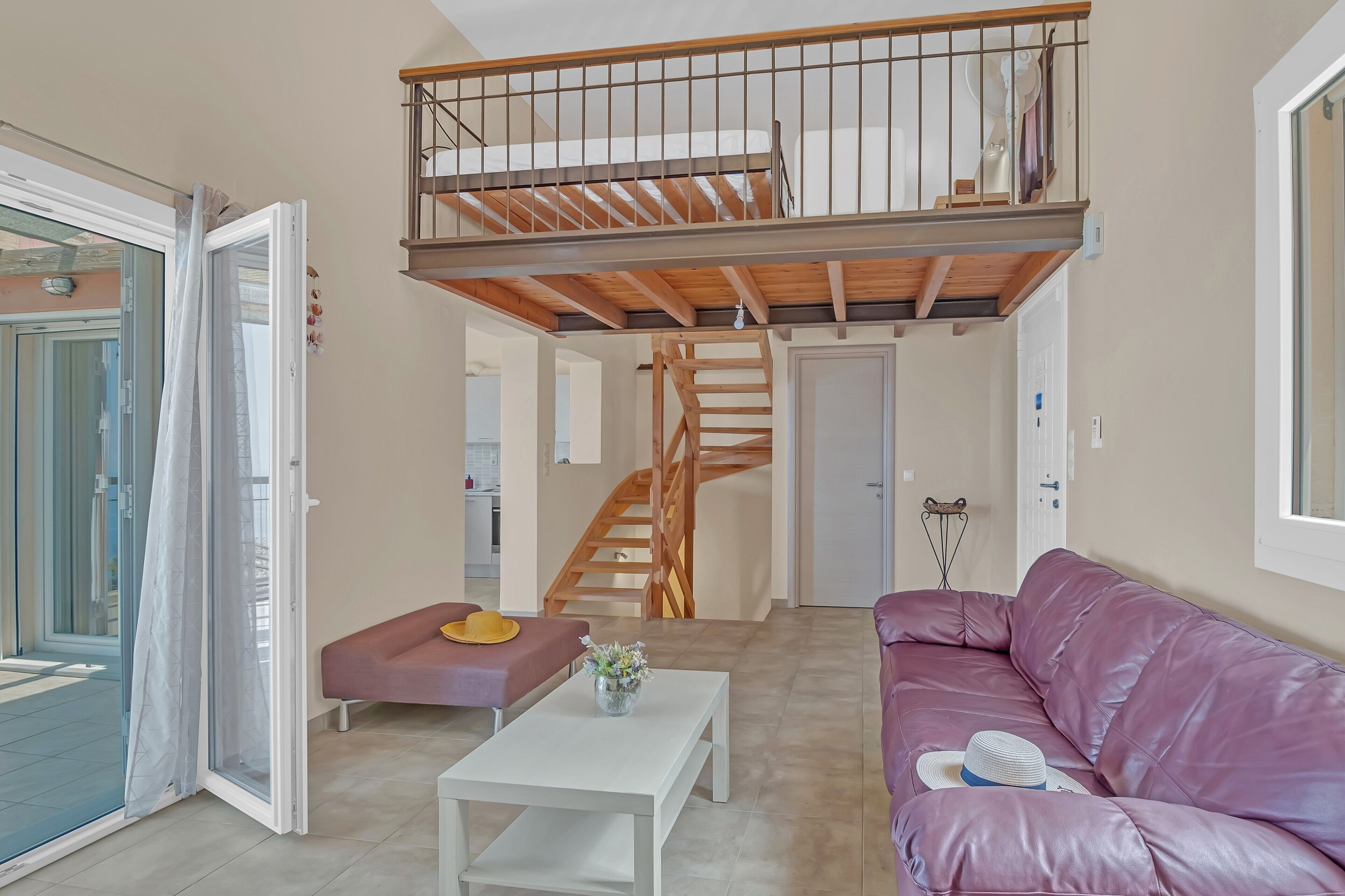 A living room with a staircase, a sofa, a coffee table, and a door leading to another room.