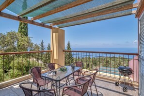 Ein Balkon mit Tisch, Stühlen, einem Grill und Meerblick.