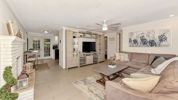 A spacious living area with a fireplace, a television, a sofa, and a dining area with a kitchen in the background. - My Venice Beach House (South Venice)