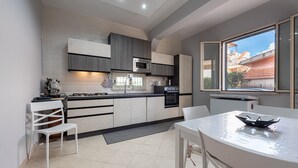 A modern kitchen with a dining area, featuring a built-in oven, microwave, and a large window offering a view of the city. - Villa 'Villino Giovanna' with Private Terrace, Wi-Fi and Air Conditioning (Trabia)