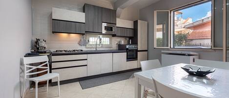 Eine moderne Küche mit Essbereich, ausgestattet mit integriertem Backofen, Mikrowelle und einem großen Fenster mit Blick auf die Stadt.