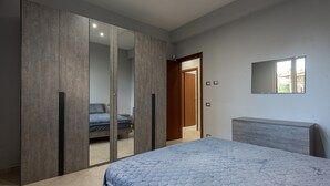 A bedroom with a bed, wardrobe, and a mirror on the wall. - Villa 'Villino Giovanna' with Private Terrace, Wi-Fi and Air Conditioning (Trabia)