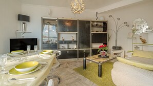 Un salon moderne comprenant un coin repas, un canapé, un téléviseur et des objets de décoration.