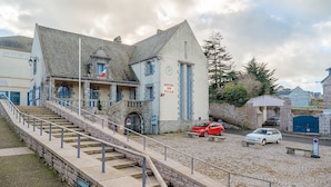 A hotel with a stone facade, a staircase leading to the entrance, and a clock on the building.