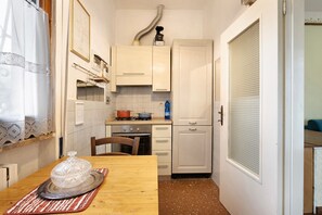 A compact kitchen with white cabinets, a stove, and a refrigerator.