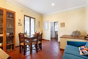 A dining area with a wooden table and chairs, a cabinet with glass doors, and a blue sofa.