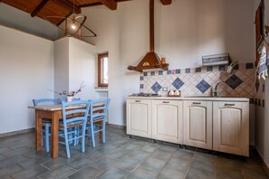 Une cuisine avec une table en bois, des chaises bleues, un pare-feu en carreaux et des armoires en bois.