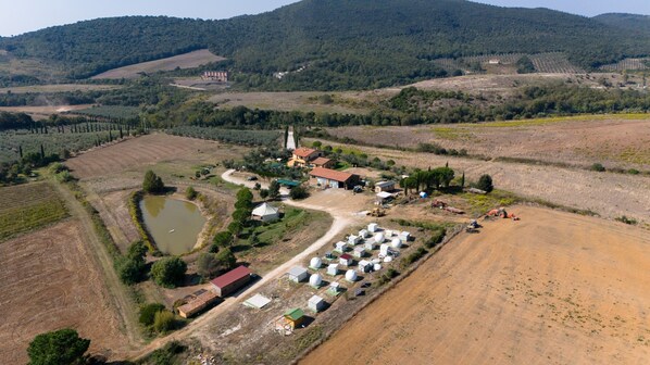 An aerial view of a rural property with multiple buildings, a large field, and a small pond.