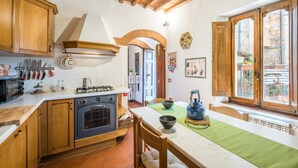 A kitchen with wooden cabinets, a stove, and a dining area with a table and chairs. - Holiday Home 'L'arco Della Fonte' with Private Terrace, Wi-Fi and Air Conditioning (Gaiole in Chianti)