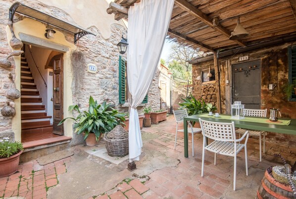 A stone building with a staircase, a table with chairs, and a sign with the number 24.
