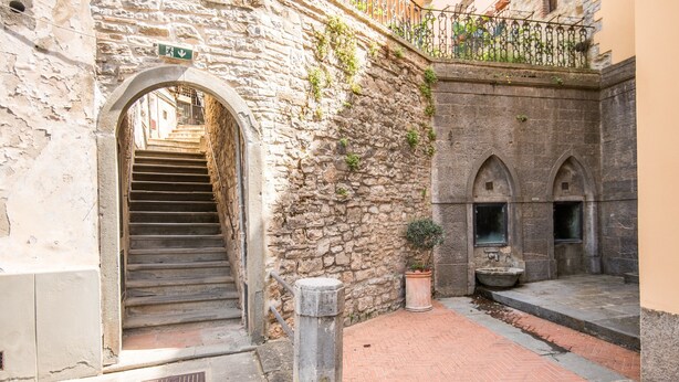 A stone staircase leading to an archway, a potted plant, and a brick-paved courtyard. - Holiday Home 'L'arco Della Fonte' with Private Terrace, Wi-Fi and Air Conditioning (Gaiole in Chianti)