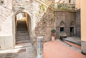 Eine Steintreppe führt zu einem Bogen, einer Topfpflanze und einem mit Ziegeln gepflasterten Innenhof.