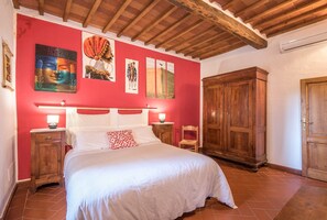 A bedroom with a bed, wooden wardrobe, and artwork on the wall.