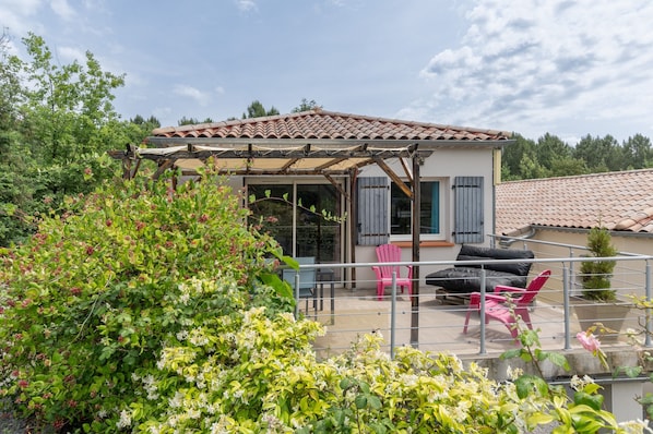 A house with a covered patio, a red chair, and a black sofa.