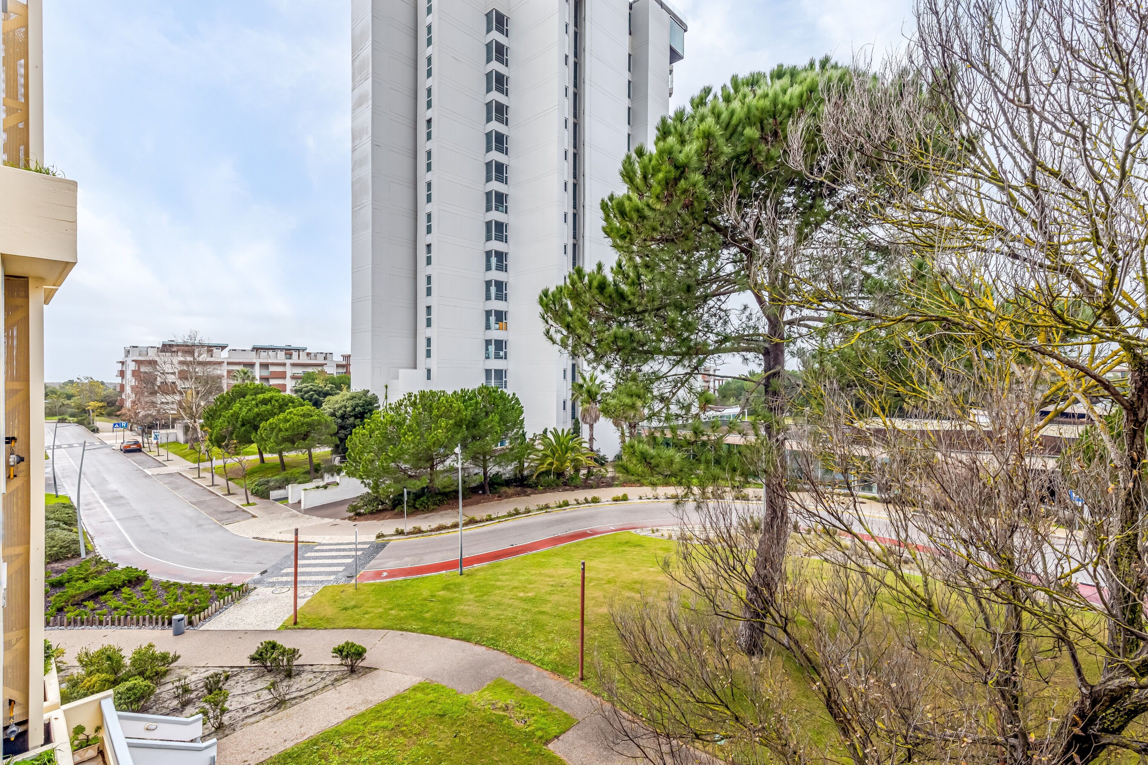 A residential area with a tall building, a curved road, and a pedestrian crossing.