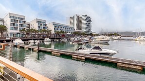 A marina with docked boats, a wooden walkway, and modern buildings with large windows. - Apartment 'Torralta' with Sea View, Wi-Fi and Air Conditioning (Carvalhal)