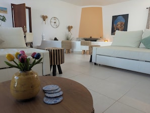 Ein Wohnzimmer mit Sofa, Couchtisch mit Vase und Untersetzern, einer Uhr, einem Buddha-Gemälde und einem Kamin.