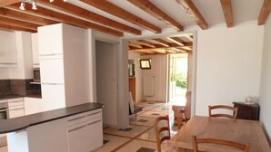 A modern kitchen with a central island, wooden dining table, and chairs. - Gîte des Cèdres - Ameugny (AMEUGNY)