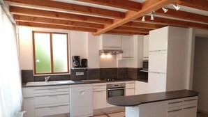 A modern kitchen with white cabinets, a black countertop, and a built-in oven. - Gîte des Cèdres - Ameugny (AMEUGNY)