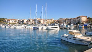 Un port de plaisance où sont amarrés de nombreux bateaux, entouré de bâtiments aux toits recouverts de tuiles rouges.