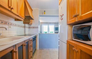 Kitchen features a sink, stove, and microwave, with a window above the sink.