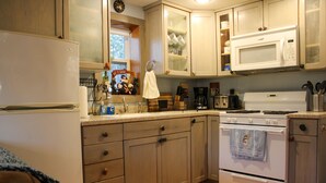 A kitchen with wooden cabinets, a white refrigerator, a microwave, and a stove. - Welcome to The Driftwood Cottage! A cozy 2-bedroom home in Grand Marais, MI. (Grand Marais)