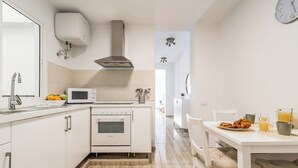 Eine Küche mit weißen Schränken, einer Mikrowelle, einem Backofen und einem Spülbecken.