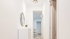 Ein Flur mit einem weißen Schrank, einem Spiegel und einer Tür zu einem weiteren Raum.