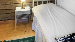 A wooden cabin-style room with a bed, a nightstand with a lamp, and a green woven rug. - 3 bedroom gorgeous home in överlida (Överlida)