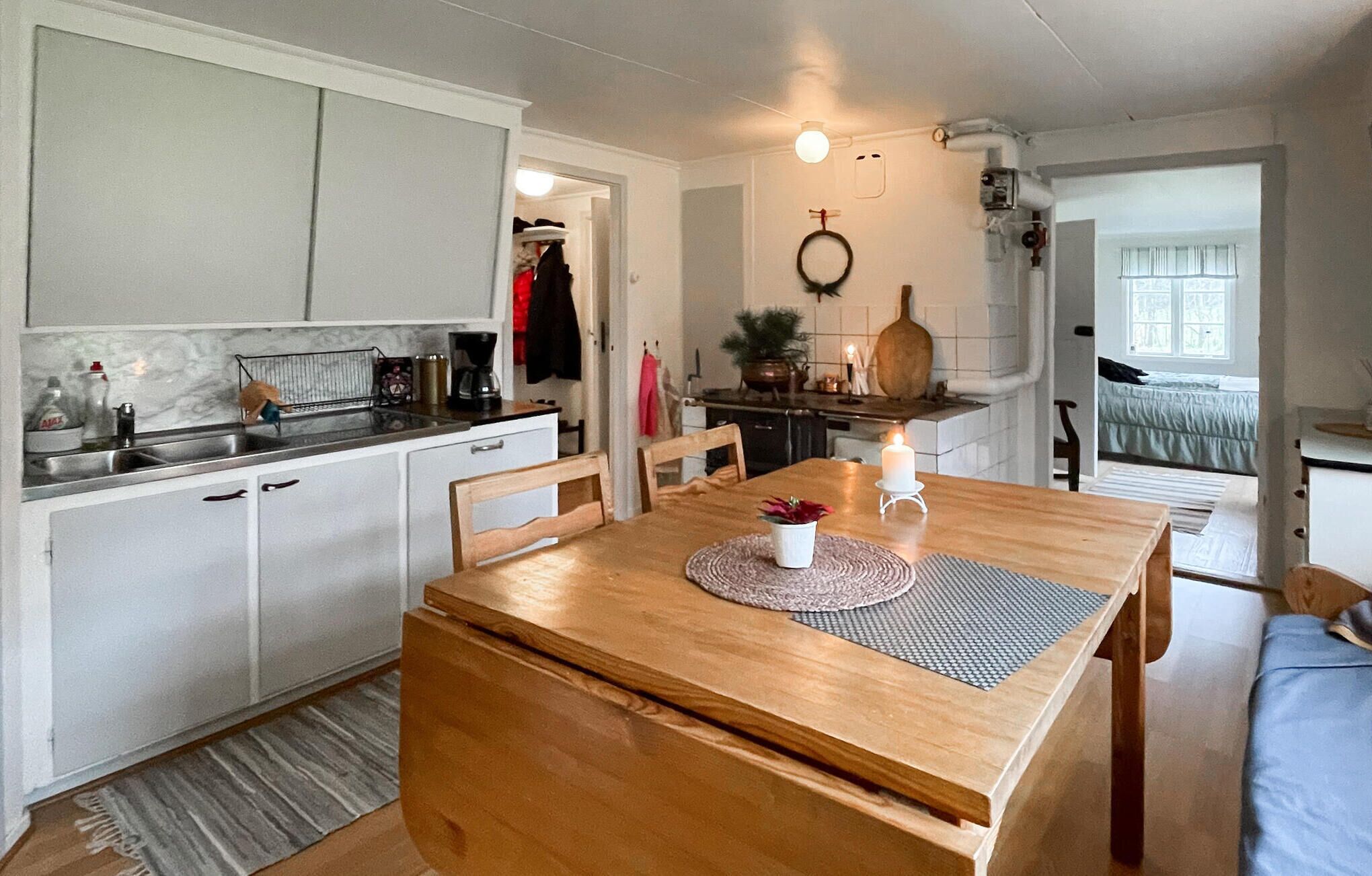 A cozy kitchen with white cabinets, a wooden dining table, and a small dining area.