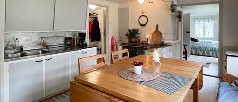 A cozy kitchen with white cabinets, a wooden dining table, and a small dining area.