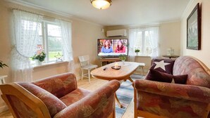 A cozy living room with two patterned armchairs, a small wooden table, and a television. - 3 bedroom gorgeous home in överlida (Överlida)