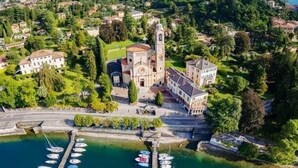 A coastal town with a prominent church, a marina with boats, and surrounding greenery.