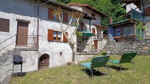 A stone building with a balcony, a small attached structure, and outdoor seating.