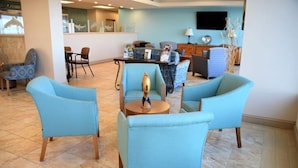 A lobby with light blue armchairs, a round table with a decorative item, and a reception desk.