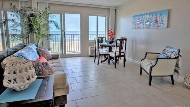 A spacious living room with a balcony, a dining area, and a painting on the wall.