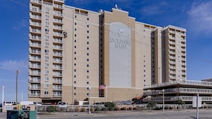 A high-rise hotel with a prominent 'Dolphin Run' sign, multiple balconies, and a parking lot in front.