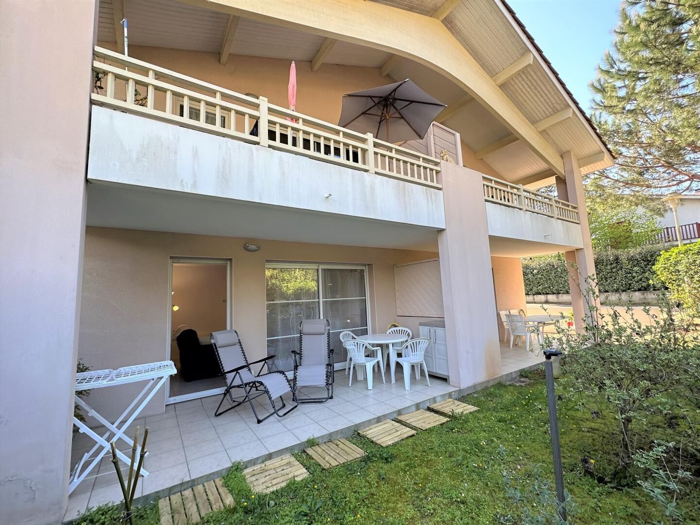 A two-story building with a balcony, outdoor seating area, and a small garden.