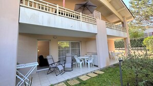 A two-story building with a balcony, outdoor seating area, and a small garden. - L'appartement Pins D97 (CAPBRETON)